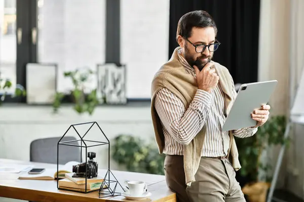 Elderly man in casual attire engages with tablet while exploring a creative workspace with plants. — Stock Photo