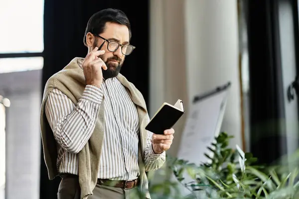 In a bright, plant filled space, a handsome elderly man thoughtfully reads in casual attire. — Stock Photo