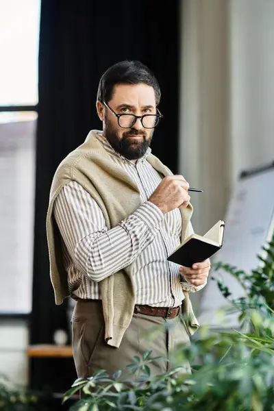 Senior man with glasses writes in his notebook, pondering ideas amid lush greenery. — Stock Photo