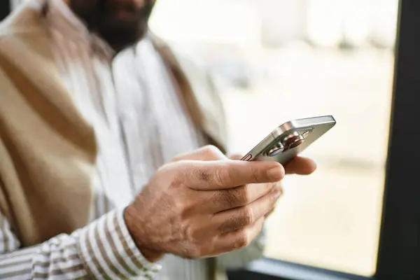Handsome senior man in casual attire browses his smartphone, absorbed in a moment of leisure. — Stock Photo