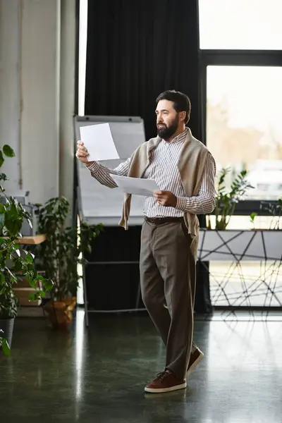 An elderly handsome man stands in a well lit room, examining important papers amidst greenery. — Stock Photo