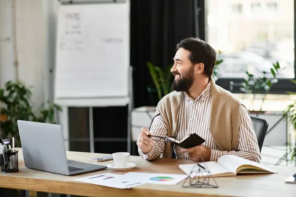 Älterer Herr lächelt, während er an seinem lässigen Schreibtisch im Büro Ideen in einem Notizbuch aufschreibt — Stockfoto