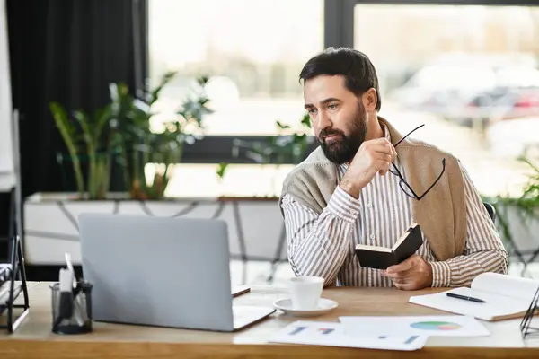 In a stylish office, a handsome elderly man writes notes and sips coffee in thought. — Stock Photo