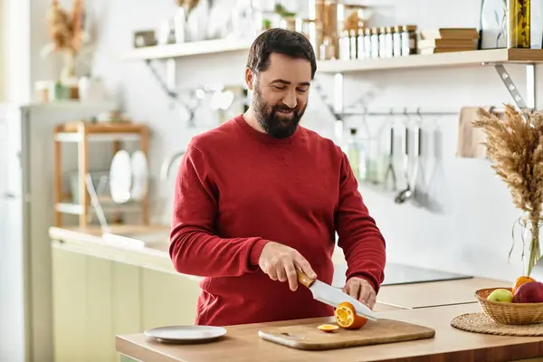 Handsome senior man slices fresh fruit with a smile, spreading joy in a sunlit kitchen. — Stock Photo