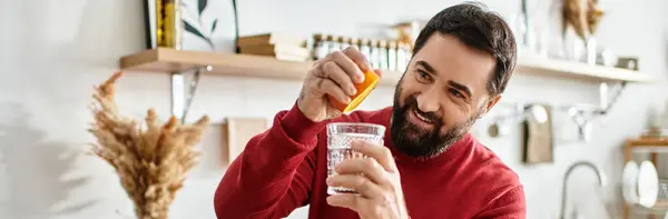 A handsome elderly man prepares a vibrant drink with a cheerful smile in a warm kitchen. — Stock Photo
