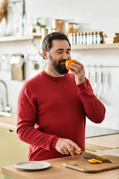 A charming senior man enjoys the scent of a fresh orange in a cozy setting. — Stock Photo