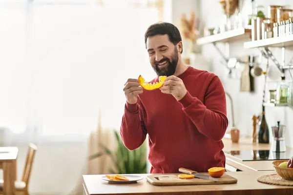 Elderly man enjoys slicing and savoring vibrant fruit while cooking in a cozy kitchen setting. — Stock Photo