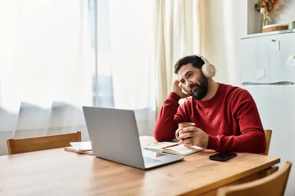 In a warm kitchen, an attractive elderly man sits at a wooden table, deep in thought with a cup. — Stock Photo
