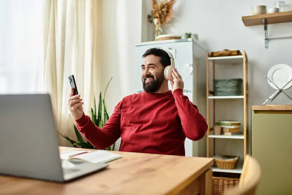 Handsome senior man smiles while listening to music on his headphones and using a smartphone. — Stock Photo