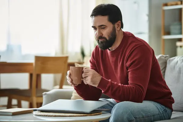 Ein eleganter älterer Herr sitzt gemütlich in einem gemütlichen Wohnzimmer und genießt sein dampfendes Getränk. — Stockfoto