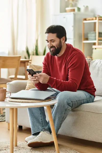 An attractive older man relaxed in casual attire, happily engaged with his smartphone at home. — Stock Photo