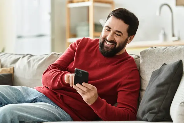 A charming elderly man happily browses his smartphone in a cozy living room. — Stock Photo