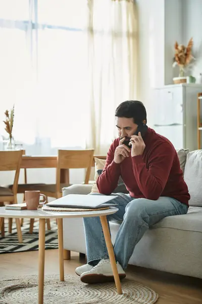 An elderly man relaxes in his living room, chatting on the phone in his cozy space. — Stock Photo