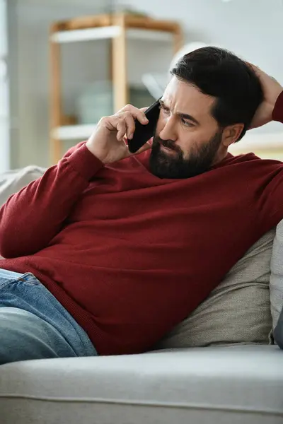 Elderly man dressed in casual attire engages in a thoughtful phone conversation while relaxing. — Stock Photo