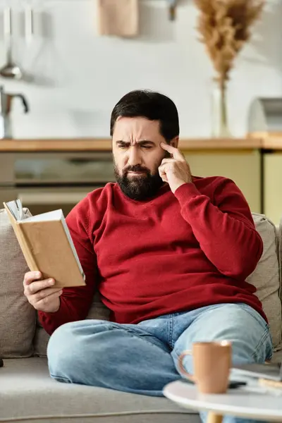 An elderly man in casual attire absorbed in a book, enjoying a tranquil afternoon at home. — Stock Photo
