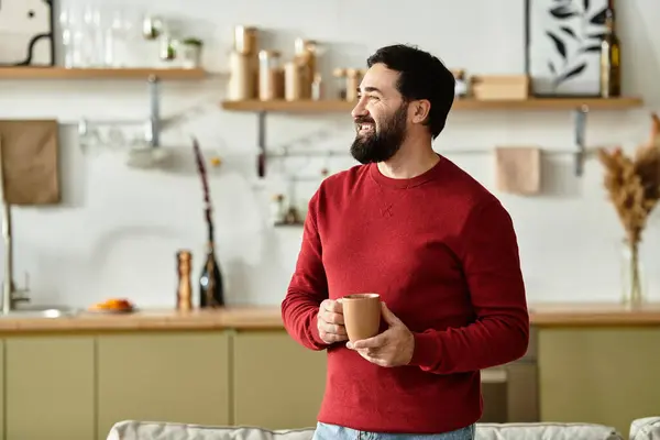 A handsome elderly man in casual wear smiles with a warm drink in a stylish kitchen. — Stock Photo