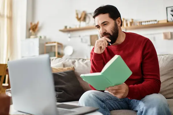 An elderly man casually dressed is deeply focused on his book while seated on a comfortable couch. — Stock Photo
