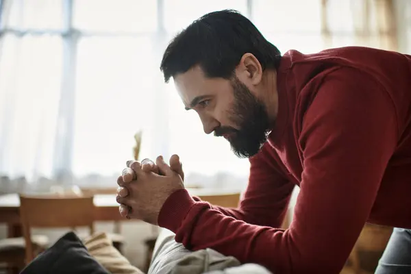 Handsome older gentleman leans forward with contemplative expression in a warm, inviting space. — Stock Photo