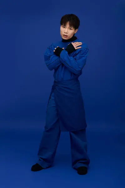 Striking young man exudes charm while showcasing a modern outfit in a vibrant blue setting. — Stock Photo