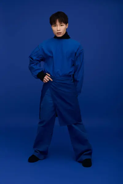 Ein hübscher junger asiatischer Mann posiert selbstbewusst in einem eleganten blauen Outfit und zeigt seinen Charme. — Stockfoto