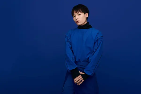 A handsome Asian man stands confidently against a vibrant blue background, exuding charm. — Stock Photo