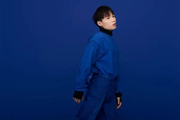A stylish young man confidently poses in a striking blue outfit, exuding charm and allure. — Stock Photo
