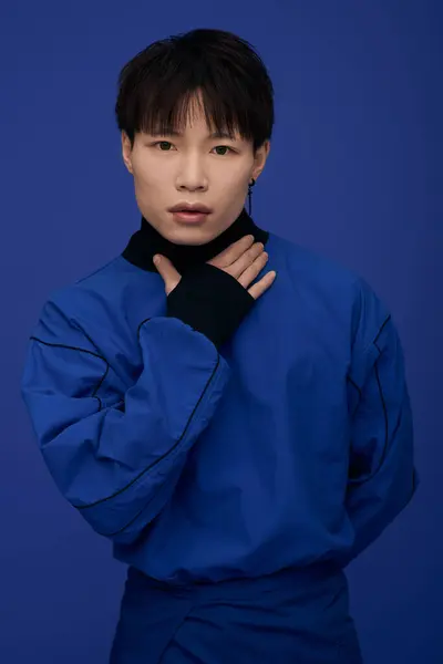 Good looking young asian male gracefully poses with a captivating expression in vivid blue. — Stock Photo
