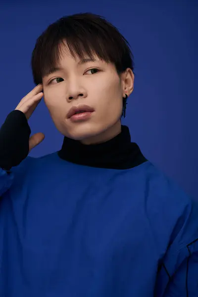 A young handsome Asian man poses expressively against a vivid blue background. — Stock Photo