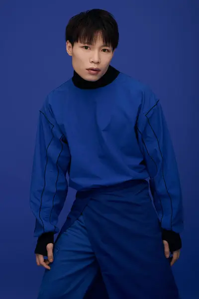 A charming young Asian man stands confidently in a striking blue outfit, showing his style. — Stock Photo
