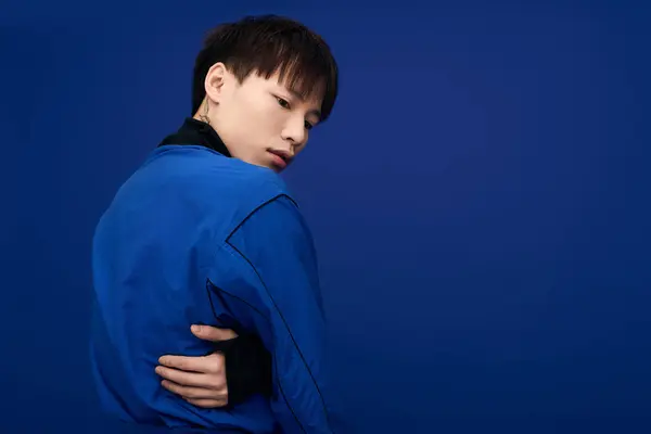 A young Asian man poses confidently, looking thoughtful in his striking blue outfit. — Stock Photo
