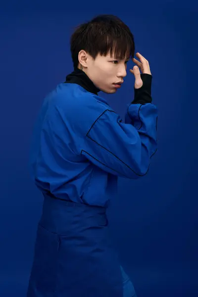A young handsome Asian man in blue poses confidently against a deep blue background. — Stock Photo
