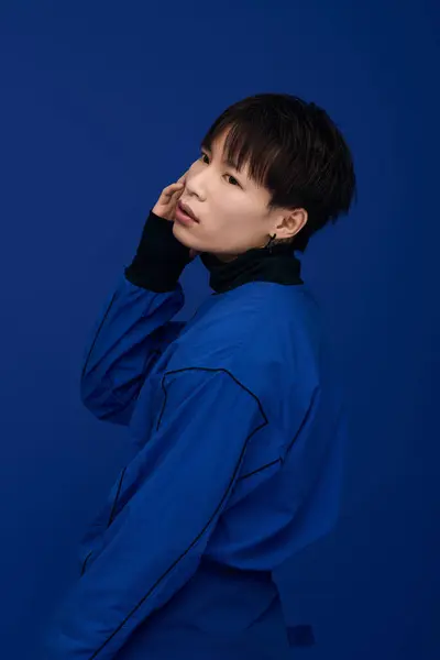 A stylish young Asian man poses confidently against a deep blue backdrop. — Stock Photo