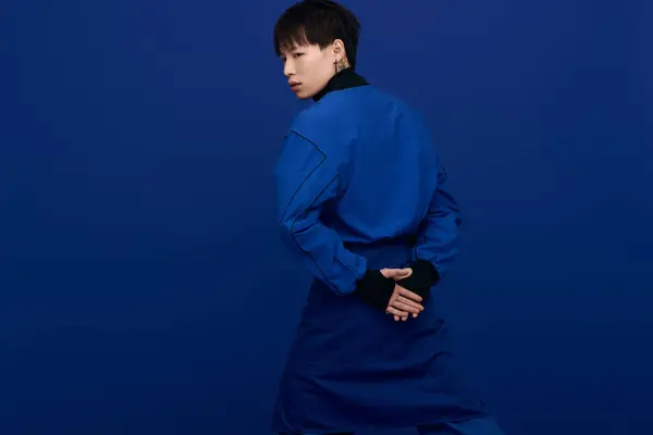 A young, attractive Asian man stands with his back turned, hands clasped, exuding charisma. — Stock Photo