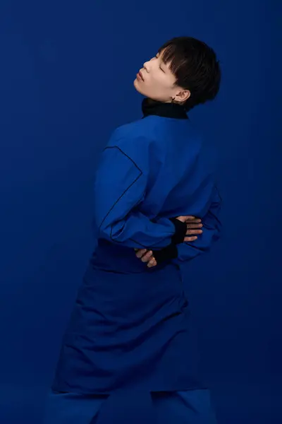 A young handsome Asian man poses in a stylish outfit against a vibrant blue background. — Stock Photo