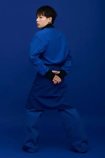 Confident young man in striking blue attire poses charm with hands behind his back. — Stock Photo