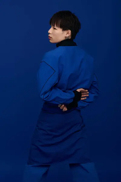 Attractive young asian man showcases a vibrant blue garment while striking a thoughtful pose. — Stock Photo