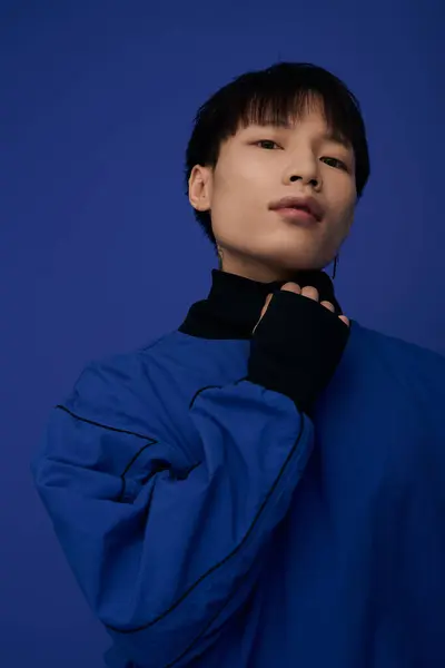 A stylish young man stands gracefully with a striking blue garment, showcasing a modern aesthetic. — Stock Photo