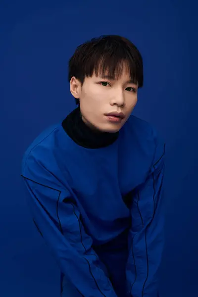 Confident young man showcases modern fashion, exuding charm with a striking blue backdrop. — Stock Photo