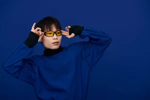 A charming young Asian man flaunts his style in bright yellow glasses and a bold blue outfit. — Stock Photo