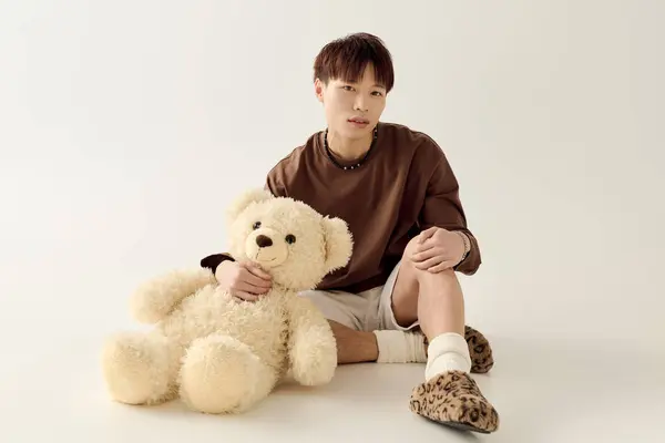 A young Asian man playfully interacts with a teddy bear in a calm setting. — Stock Photo