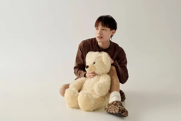 A handsome young man with a teddy bear, embodying relaxed charm and innocence. — Stock Photo