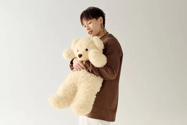 A charming young man cradles an oversized teddy bear, showcasing a playful and heartwarming vibe. — Stock Photo