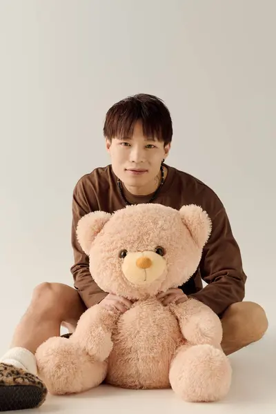A cheerful young handsome asian man holds a cuddly teddy bear, radiating warmth and happiness. — Stock Photo
