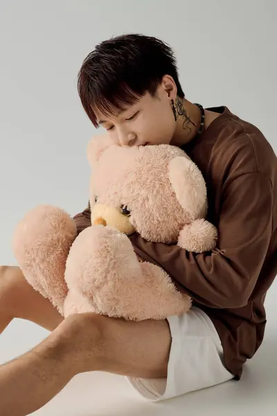 Jeune homme confortable profite d'un moment tendre avec un grand ours en peluche dans un cadre accueillant. — Photo de stock