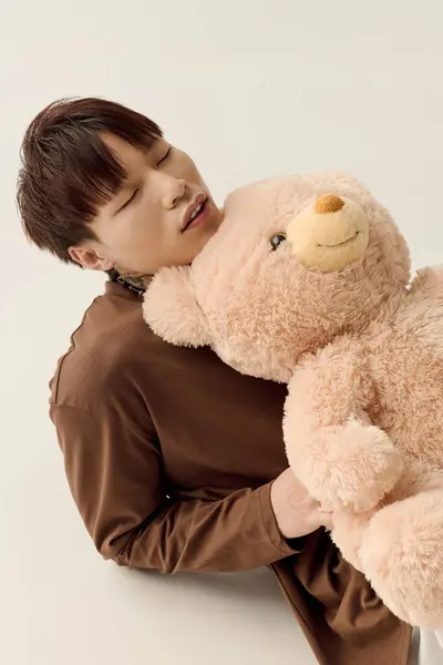 A young Asian man cherishes a quiet moment with a teddy bear, surrounded by peace. — Stock Photo