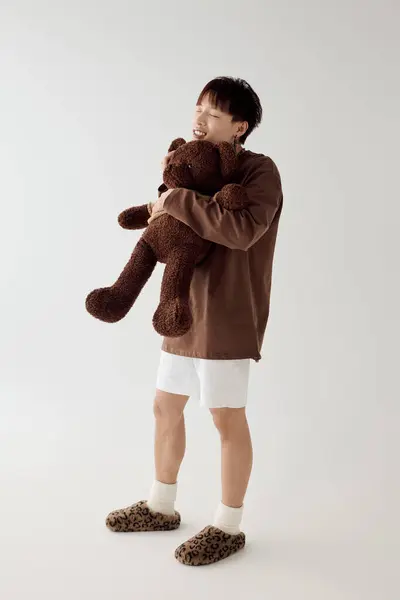 A charming young man hugs a large teddy bear in a bright, cozy room. — Stock Photo