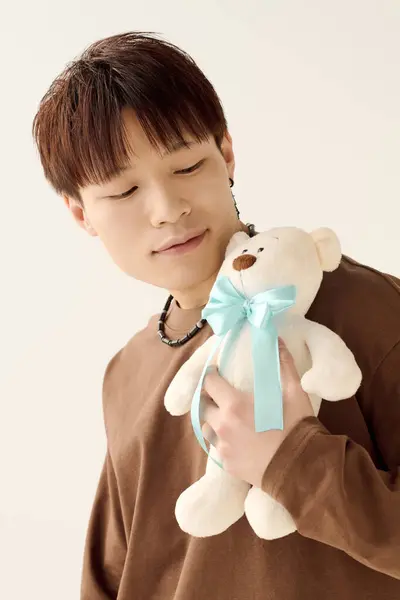 A young man gently holds a plush bear, reflecting warmth in a peaceful setting. — Stock Photo