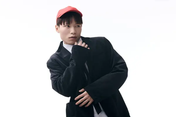 A young Asian man in a trendy outfit poses confidently with a playful expression in daylight. — Stock Photo