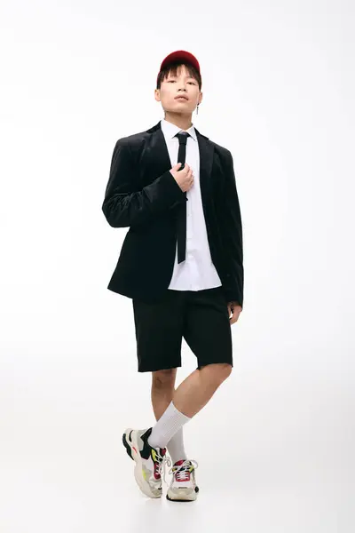 Jovem confiante vestindo um casaco de terno preto elegante sobre shorts golpeia uma pose em estúdio. — Fotografia de Stock