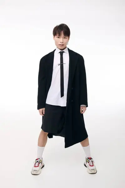 A handsome young Asian man confidently models a striking outfit in a bright studio. — Stock Photo